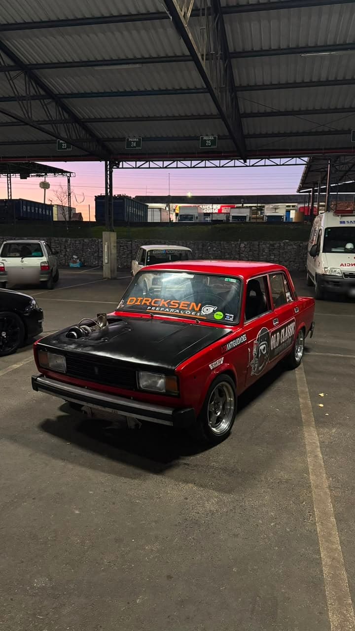 Lada Laika vermelho de capô preto e turbo aparente, sob cobertura ao pôr do sol, com faixa DIRCKSEN PREPARAÇÕES no para-brisa